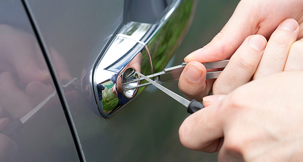 person using lock picking tools on car door lock demonstrating advanced skills in unlocking cars quickly and efficiently for 12 essential techniques