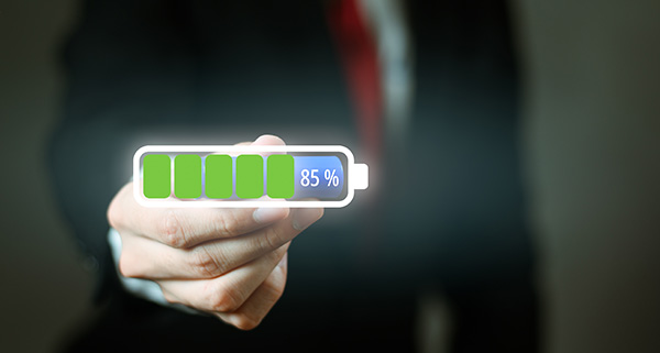 businessman holding a battery icon displaying 85 percent charge representing energy efficiency and productivity in the workplace with emphasis on the importance of maintaining 16 key skills