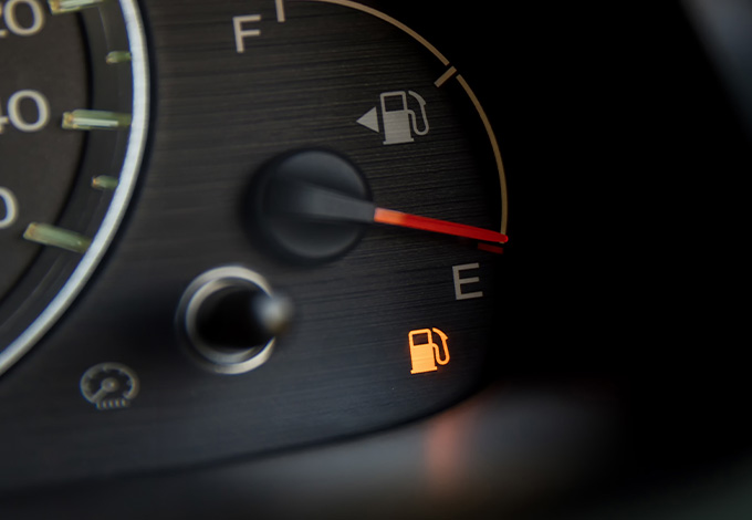 fuel gauge on empty indicating low fuel level with warning light illuminated for two reasons