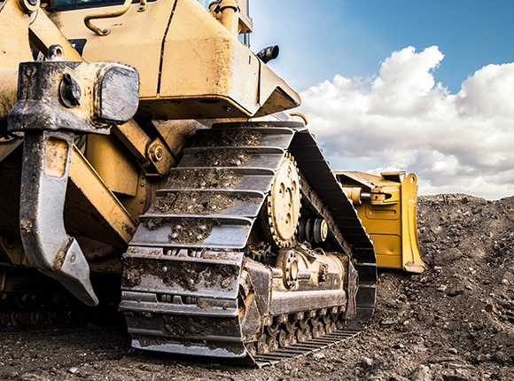 yellow bulldozer on construction site with visible tracks and machinery against cloudy sky showcasing heavy equipment for earthmoving and excavation