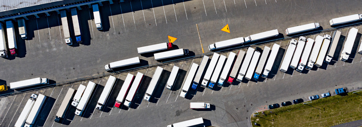 aerial view of numerous trucks parked in a lot with a focus on organization and logistics showing 5 delivery trucks and other vehicles