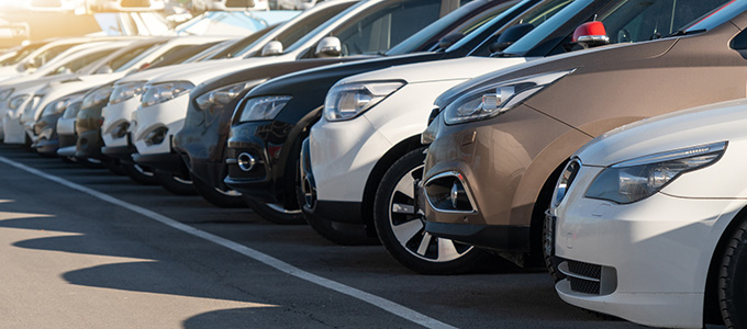 a row of parked cars in various colors including white black and brown with two cars prominently displayed in the foreground
